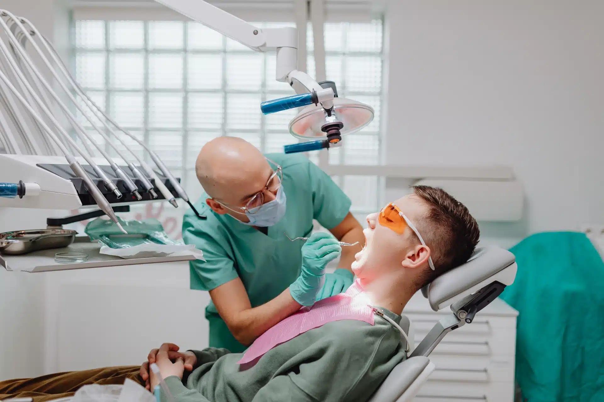 A dentist inspecting the open mouth of a patient sitting on a dental chair