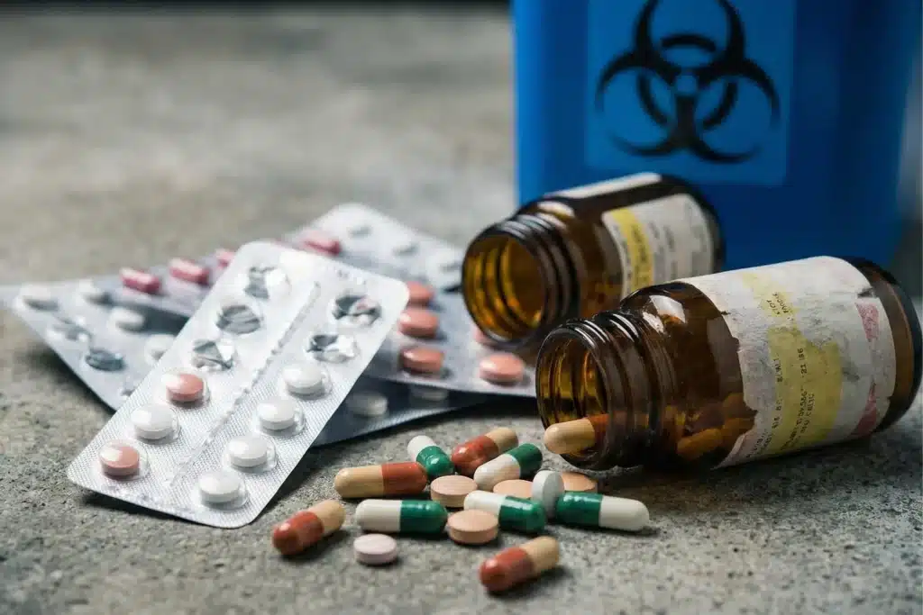 Pills and capsules spilled next to blister packs and amber prescription bottles